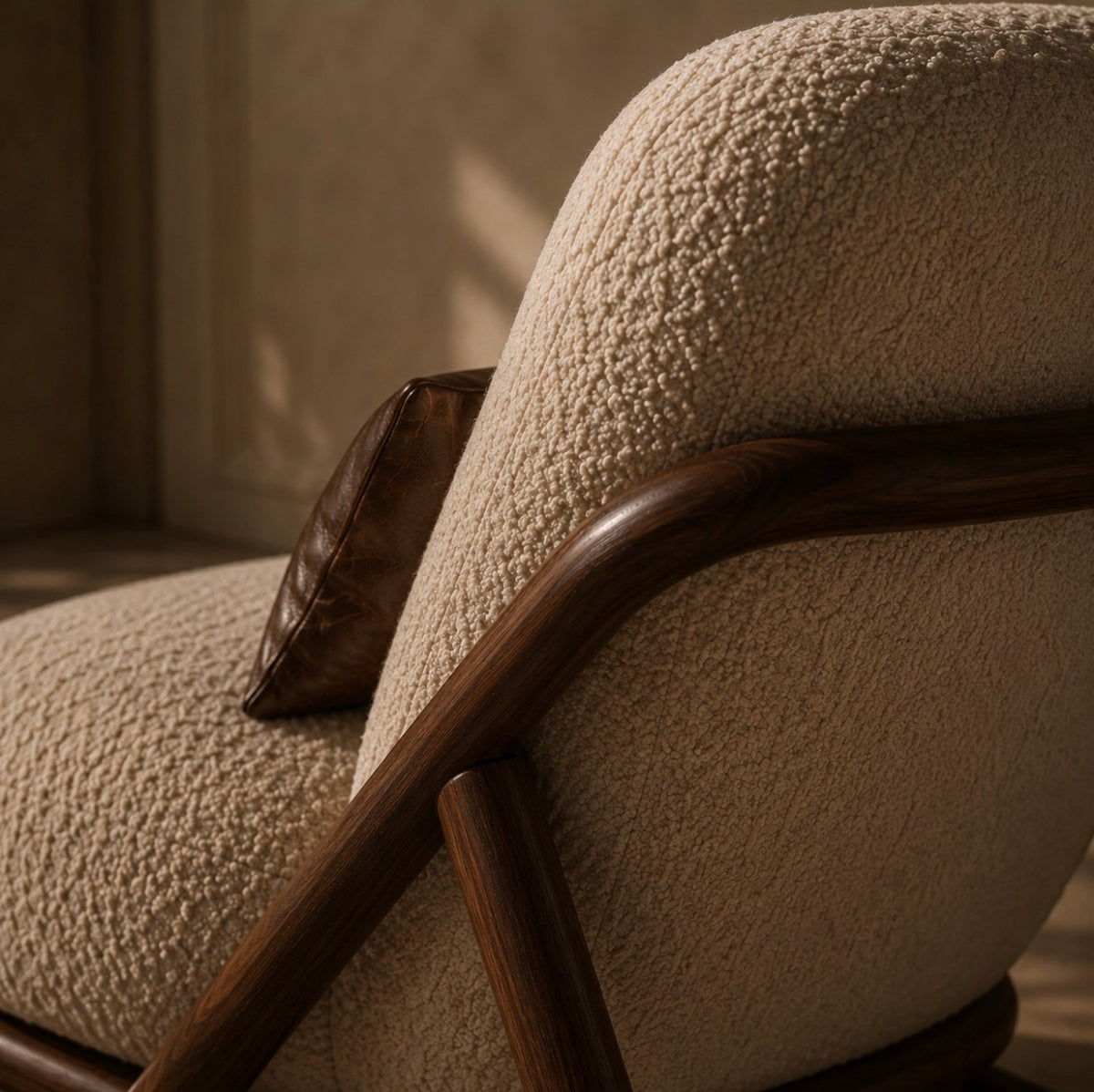 Close detail of the bent wooden arm where it meets the bouclé back